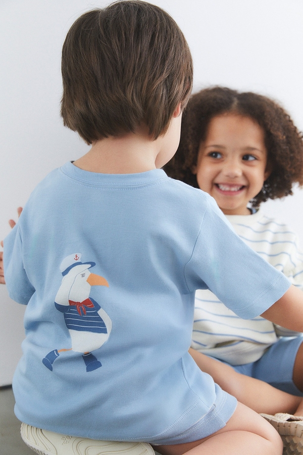 Short Sleeve Tee. Plain light blue with round necklace. Seagull printed at the back and pocket at the front. Kid model back view.