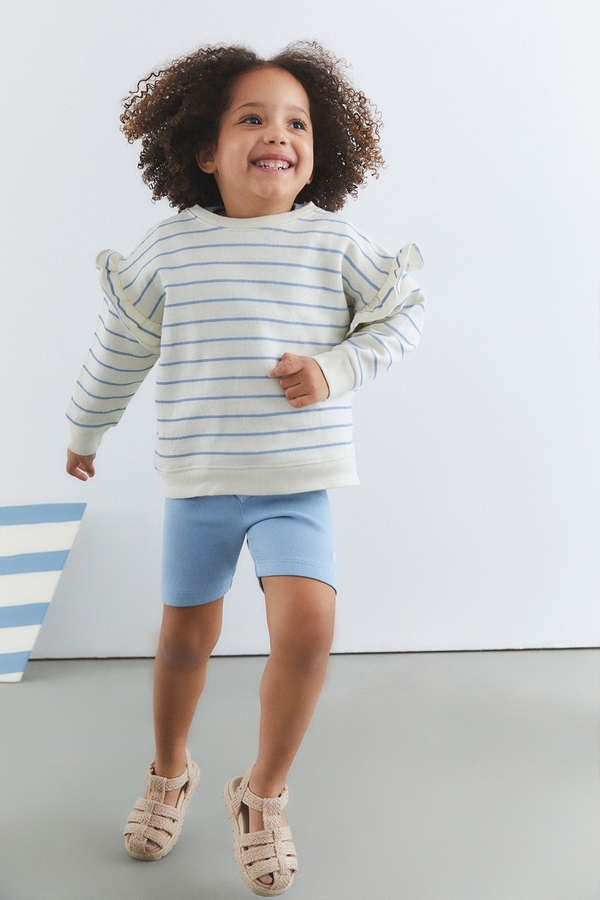 Ribbed Cotton Bike Shorts. Plain light blue with logo embreoidered at the front. Kid model view.